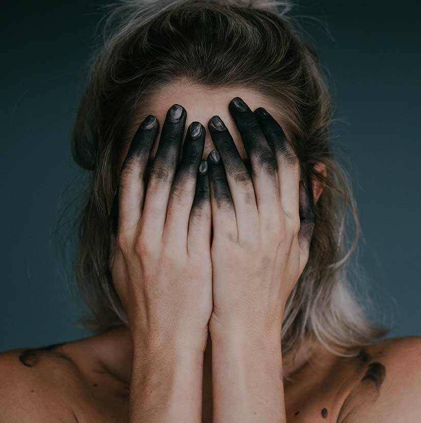 Woman with Black Fingers Covering her Face